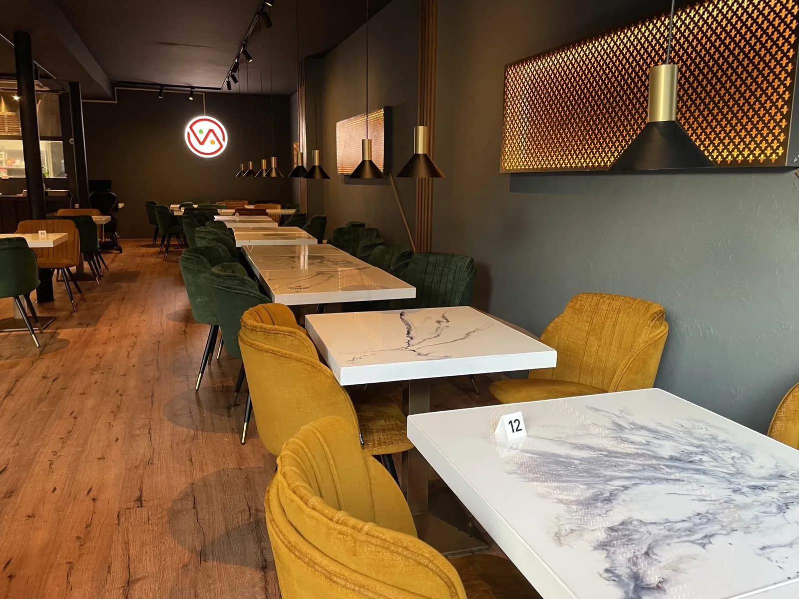 The dining room at VegNation Utrecht with the neon logo, velvet chairs and marble tables
